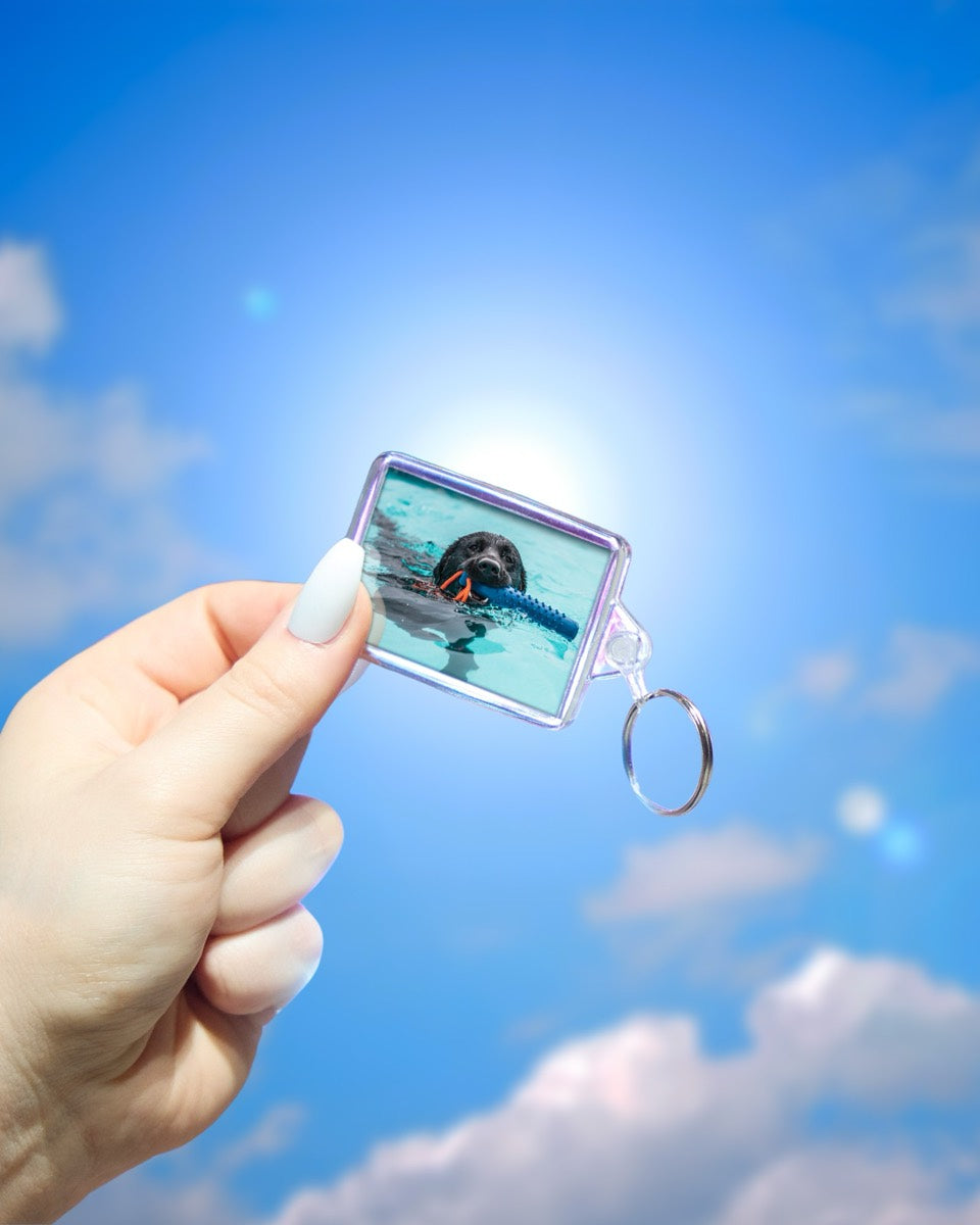 50 x 35mm personalised photo keyring held in a hand for scale, with a photo of a dog swimming
